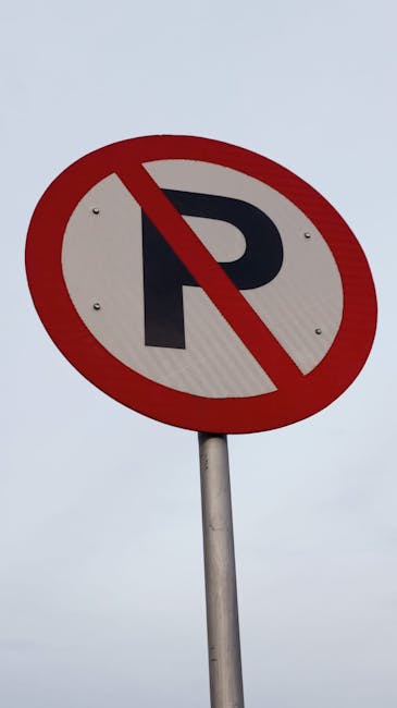 A round traffic sign with a white background, a bold black letter 'P', and a red diagonal line crossing through it, indicating no parking. The sign is mounted on a metal pole positioned in an outdoor area under an overcast sky. The background shows a grey sky with no other visible structures. This sign is relevant to road closure and temporary parking rules for Northolt moves, as noted on the webpage about house removals and relocation services by Man with Van Northolt. The sign may influence vehicular access during the home relocation and furniture transport process, which involves loading and unloading household items, such as cardboard boxes, packing materials, and furniture, at the property and loading area visible in the context of moving logistics.